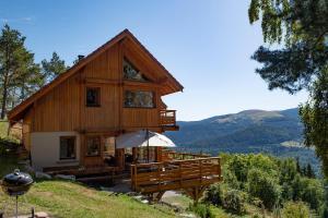 a large wooden house with an umbrella in front of it at Les Chalets de La Marcairie in Metzeral