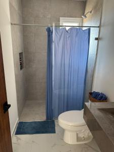 a bathroom with a shower with a toilet and a blue shower curtain at Sol y mar in Boca del Río