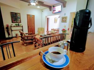 a cup of coffee sitting on a table with a coffee machine at Hotel Aluge in Santo Domingo