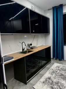 a kitchen with a sink and black cabinets at Seven Day in Bishkek