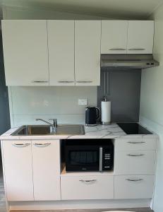 a white kitchen with a sink and a microwave at Suite Ten10 in Te Awamutu