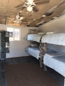 a room with three bunk beds and a ceiling fan at Checkpoint in Rosarito