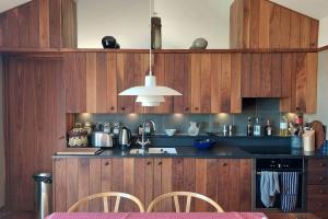 a kitchen with wooden cabinets and a sink with chairs at Architect-designed Suffolk Barn, spectacular view in Blythburgh