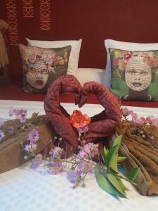 ein Bett mit zwei herzförmigen Handtüchern und Blumen darauf in der Unterkunft RICA RESIDENCE in Dumbéa
