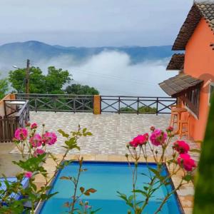 a pool with pink flowers in front of a house at Belaninha in Guaramiranga