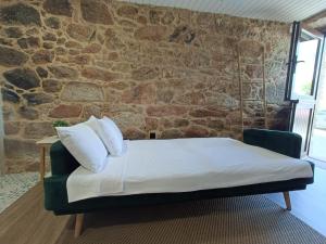 a bed in a room with a stone wall at A casiña do Pozo in Crucero