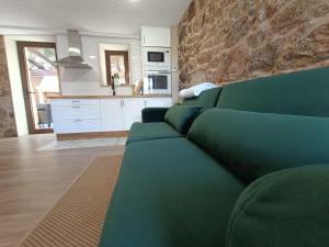 a living room with a green couch and a kitchen at A casiña do Pozo in Crucero