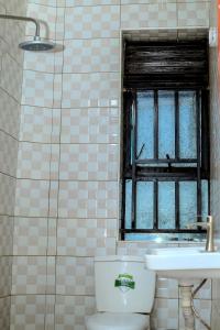 baño con aseo y lavabo y ventana en EQUATOR GATES HOTEL, en Bulenga