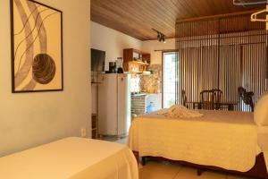 a room with two beds and a kitchen with a refrigerator at Apartamentos Mandala in Itacaré