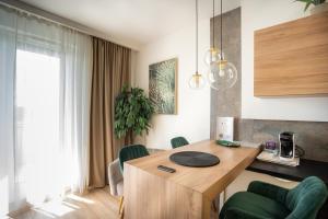 uma sala de estar com uma mesa de madeira e cadeiras verdes em Meridien Home Apartment em Fonyód
