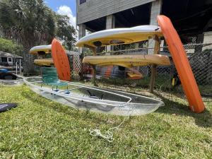 a group of surfboards and a boat on the grass at Waterfront-ClearKayak-Paddle Boards-BBQ-Beach Gear in Spring Hill