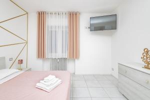 a white bedroom with a pink bed and a tv at Holidays in Lecco
