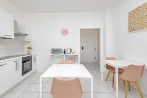 a white kitchen with a white table and chairs at Holidays in Lecco