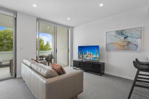 uma sala de estar com um sofá e uma televisão de ecrã plano em Sleek 2-Bed with Balcony and Communal BBQ Area em Brisbane