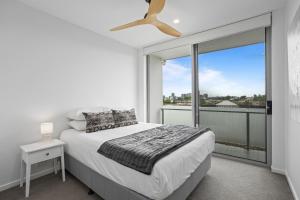 a bedroom with a bed and a large window at Sleek 2-Bed with Balcony and Communal BBQ Area in Brisbane