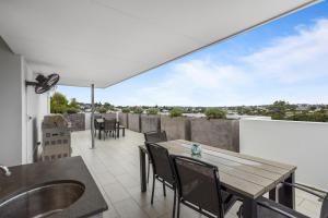 a patio with a wooden table and chairs on a balcony at Sleek 2-Bed with Balcony and Communal BBQ Area in Brisbane