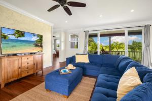 a living room with a blue couch and a tv at Kolepa Kai in Koloa