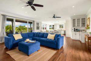 a living room with a blue couch and a kitchen at Kolepa Kai in Koloa