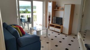 a living room with a blue couch and a glass table at Apartments by the sea Njivice, Krk - 5296 in Njivice