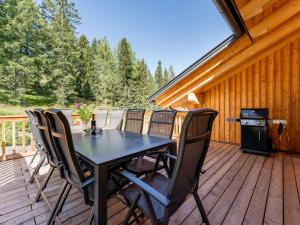 une table et des chaises noires sur une terrasse en bois dans l'établissement Atemlos Mountain Chalet, à Turracher Höhe
