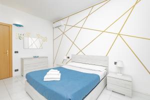 ein weißes Schlafzimmer mit einem blauen Bett und einer geometrischen Wand in der Unterkunft CasaBlanca in Lecco