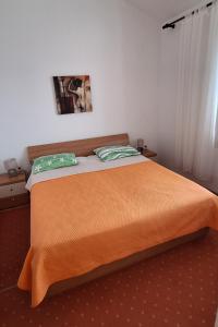ein Schlafzimmer mit einem Bett mit einer orangefarbenen Decke in der Unterkunft Apartments by the sea Rogoznica - 7499 in Rogoznica