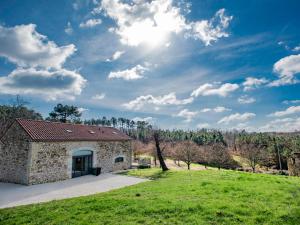 uma casa de pedra com um campo verde e céu em La grande Grange em Loubejac