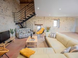uma sala de estar com um sofá e uma televisão em La grande Grange em Loubejac