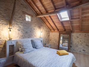 1 dormitorio con 1 cama blanca en una pared de piedra en La grande Grange en Loubejac