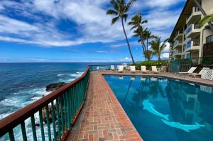 a swimming pool with a view of the ocean at Poipu Shores 101A in Koloa