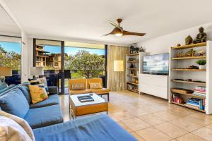 a living room with a blue couch and a tv at Makahuena 1204 Ocean View in Koloa