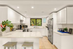 a white kitchen with white cabinets and a window at Makahuena 1204 Ocean View in Koloa