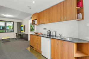 a kitchen with wooden cabinets and a counter top at Contemporary 1-Bed First Floor Unit with Pool in Sydney