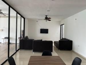 a living room with black couches and a flat screen tv at Casa Dzitya in Mérida