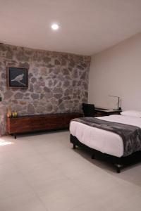 um quarto com uma cama e uma parede de pedra em Quinta Pichón em Tepic