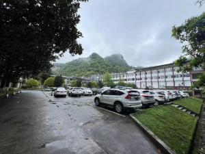 um parque de estacionamento com carros estacionados em frente a um edifício em Rivulet Mountain Hotel - Zhangjiajie Forest Park Scenic Area em Zhangjiajie