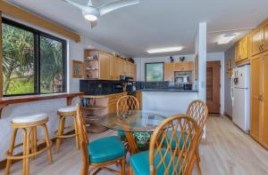a kitchen with a glass table and chairs in a kitchen at Poipu Shores 207A in Koloa