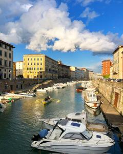 a group of boats docked in a river with buildings at Maison Bohémienne in Livorno