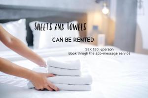 a person is putting towels on a bed at Hällestrand Vandrarhem - Lägenhet "Laxen" in Strömstad
