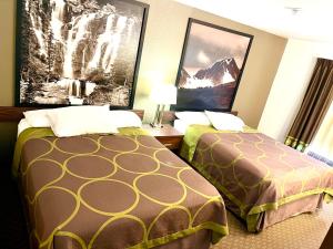 a hotel room with two beds and pictures on the wall at Super 8 by Wyndham Hinton in Hinton
