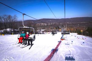a group of people sitting on a ski lift at 10 guest Ski Chalet Pools Golf Ski Hike in Vernon Township