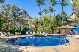 - une piscine dans un complexe avec des palmiers dans l'établissement Waikomo Stream Villas 332, à Koloa