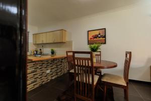a kitchen with a table and chairs and a counter at Lucian Cottages in Munyonyo