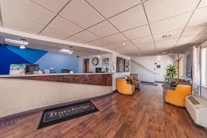 una hall con ufficio, zona di attesa e sedie arancioni di Travelodge by Wyndham Colorado Springs Airport/Peterson AFB a Colorado Springs