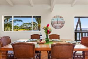 uma sala de jantar com uma mesa de madeira e cadeiras em Kauai Bay House, Ocean Front em Koloa