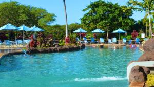 uma piscina com guarda-sóis e cadeiras azuis em Kauai Bay House, Ocean Front em Koloa