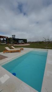 uma grande piscina azul com 2 espreguiçadeiras em Son Del Viento em La Cumbre