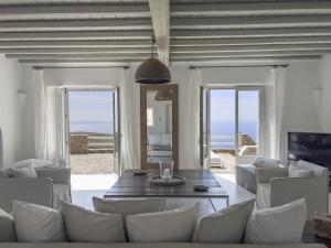 una sala de estar con mesa y sillas y el océano en Villa Prive 88 Mykonos, en Fanari