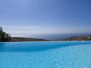 una piscina de agua azul con el océano en el fondo en Villa Prive 88 Mykonos, en Fanari