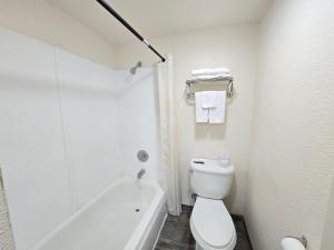 a white bathroom with a toilet and a bath tub at Peach City Inn - Marysville/Yuba City in Marysville